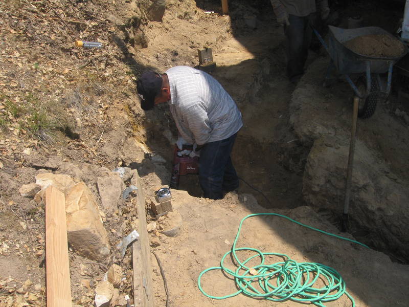 Around back, hammering out the footing...